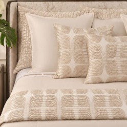 Beige and cream bed styled with Puccini 24×24 pillows and matching throw from the Judith Leiber Couture by Ann Gish collection, featuring gold embroidered butterfly motifs. — THPUK‑IVO PWPU2424-IVO